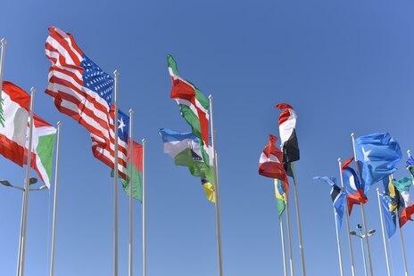 Flaggen unterschiedlicher Nationen an Fahnenmästen.